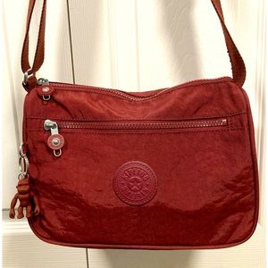 NWOT Kipling Callie in the color Intense Maroon. Dimensions:H7.5xL10.5xD4”